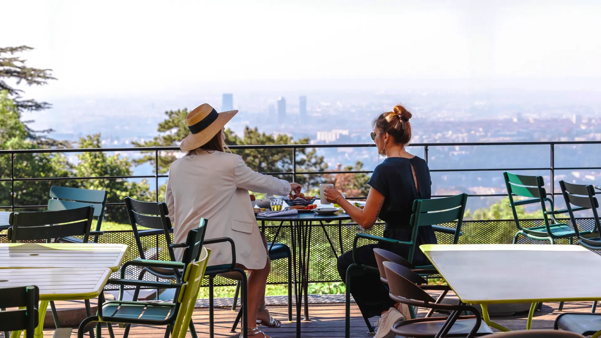 Deux femmes prennent un café en terrasse panoramique.