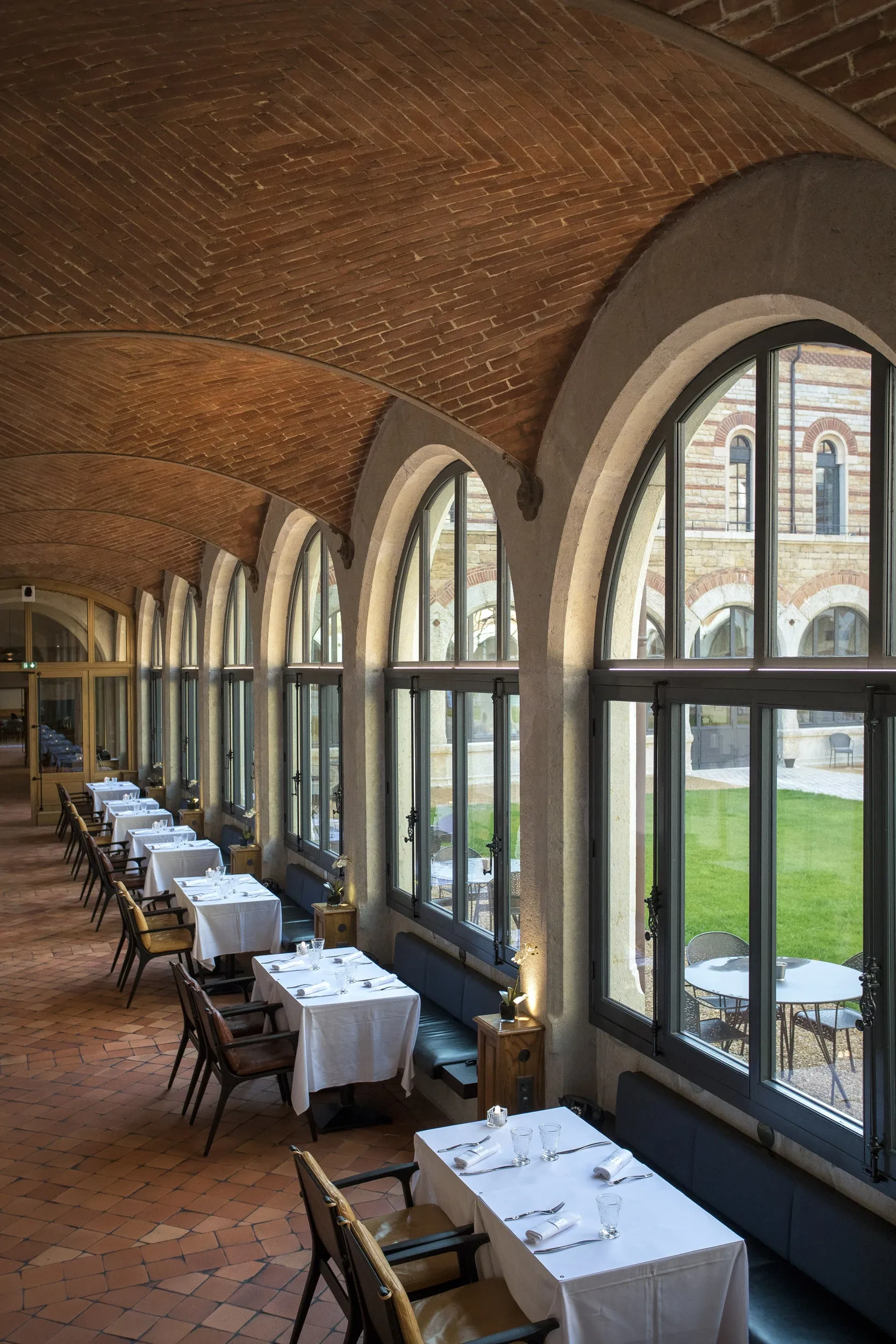 Salle à manger avec grandes fenêtres et tables dressées.